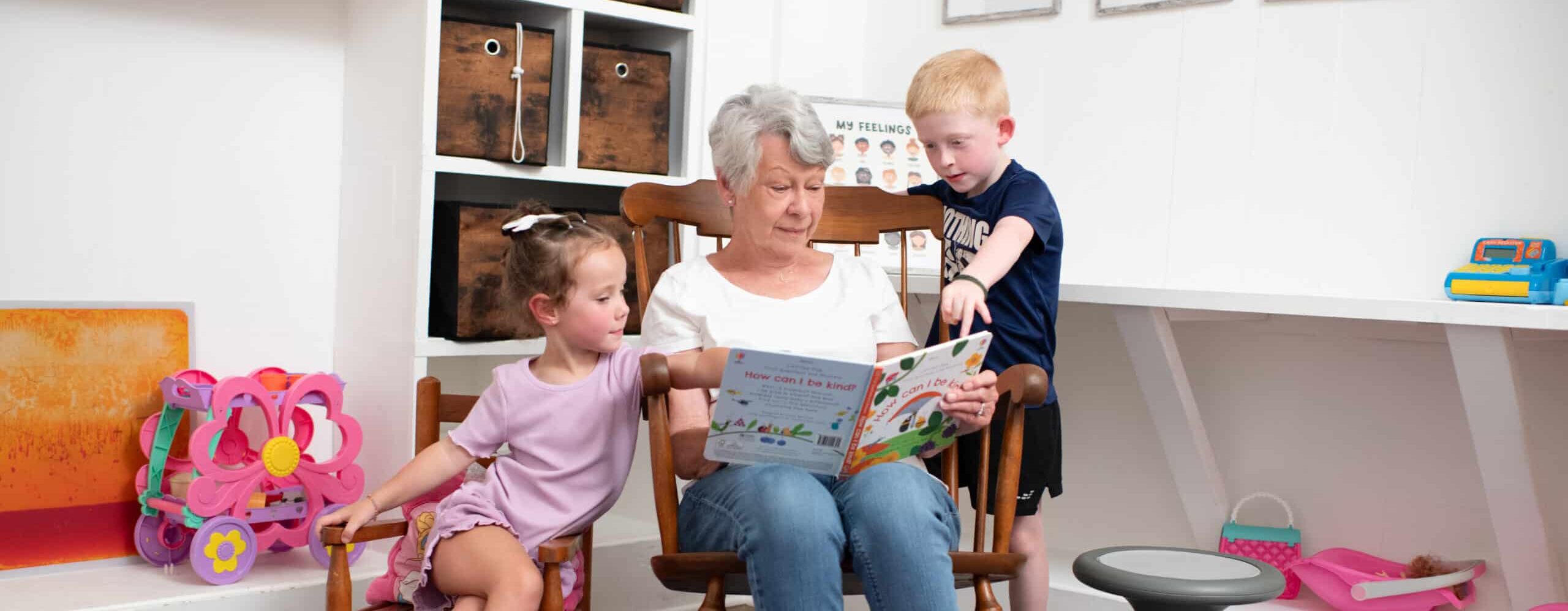 Older woman reading a book to two young children