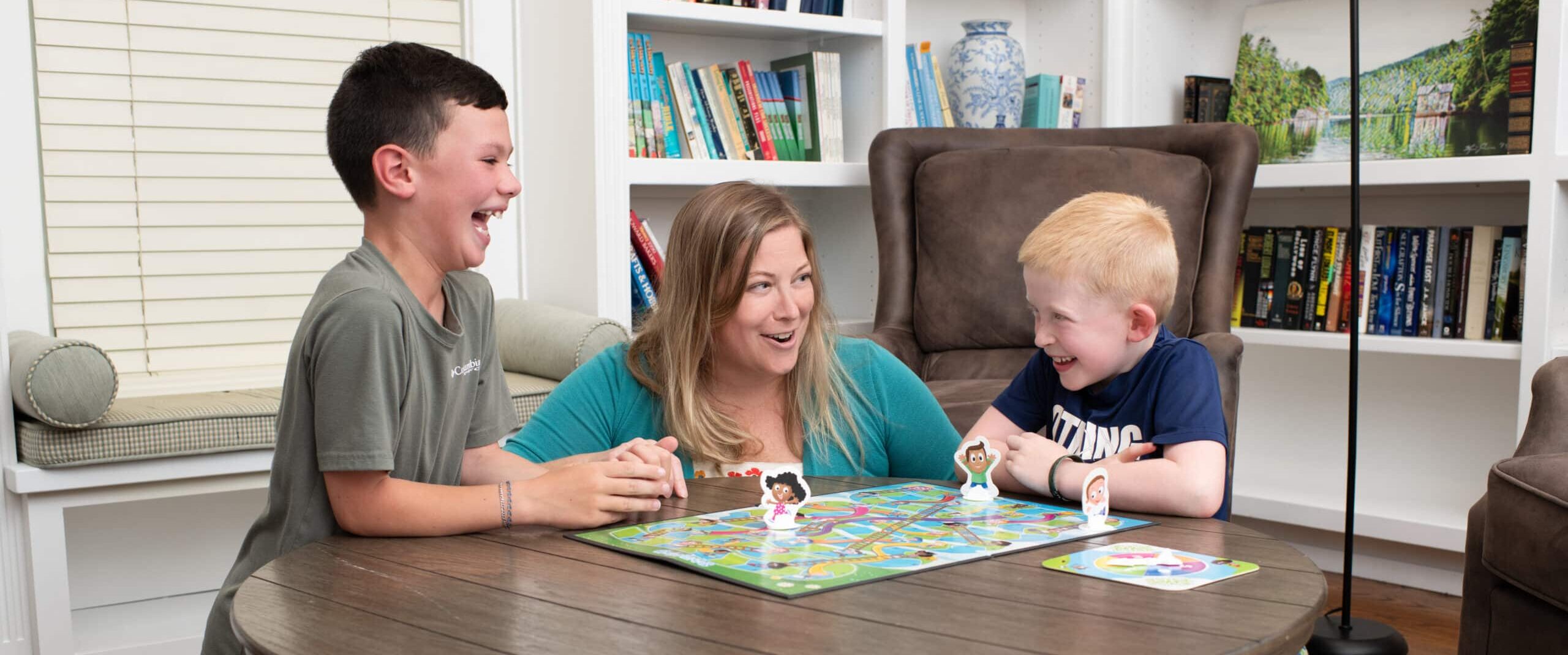 Woman playing board game with two elementary aged boys