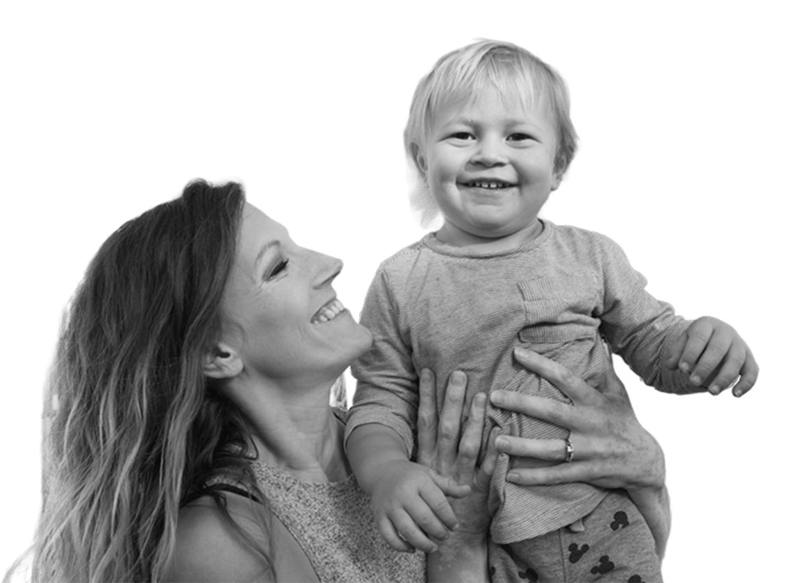 A young mother holding smiling toddler in a black and white photo